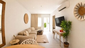 A modern living room with a sofa, TV, and a plant. - Aruba Coco het Tropische Luxe Verblijf met een Fantastische Centrale Ligging (Oranjestad)