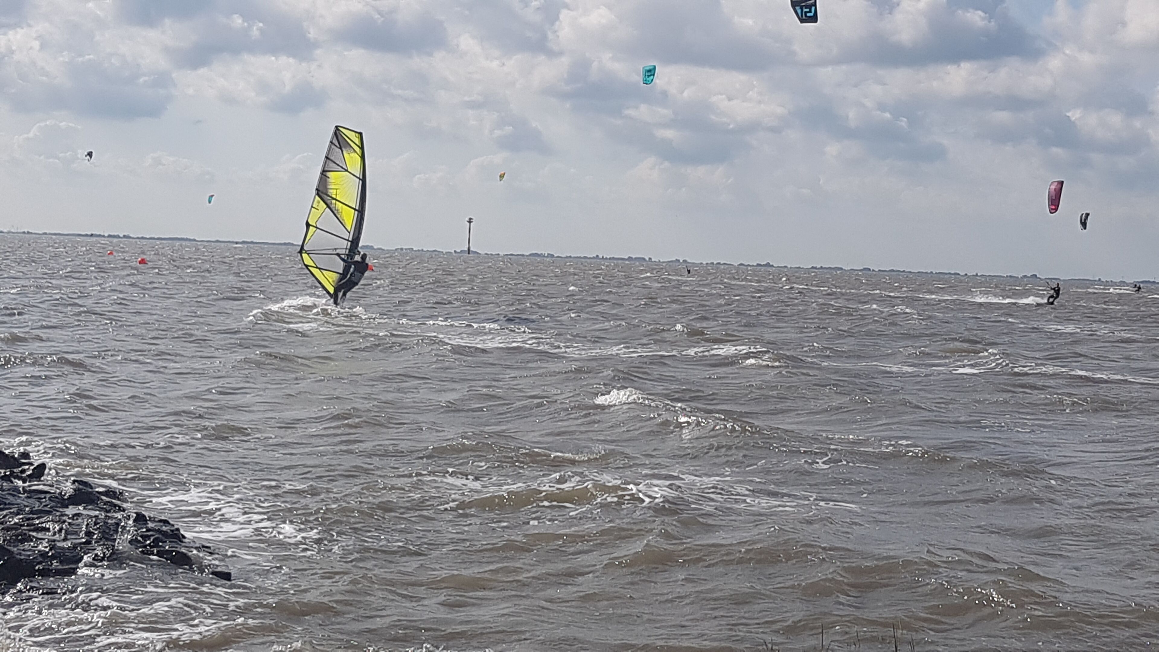 Ein Gewässer mit mehreren Windsurfern.