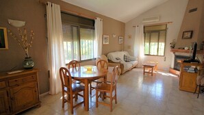 Un salon chaleureux comprenant un coin repas, un canapé, une cheminée et un téléviseur.