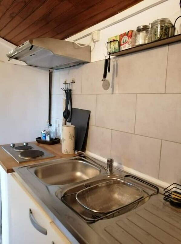 Kitchen area with double sink, stove, and metal drying rack.