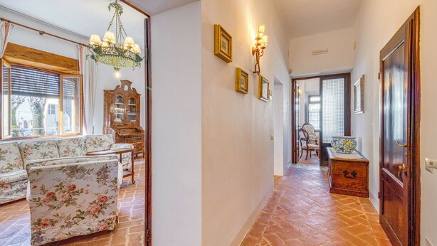 A hallway with a floral sofa, a wooden cabinet, and a chandelier. - Chianti Classico Home Panoramic View (Castellina in Chianti)