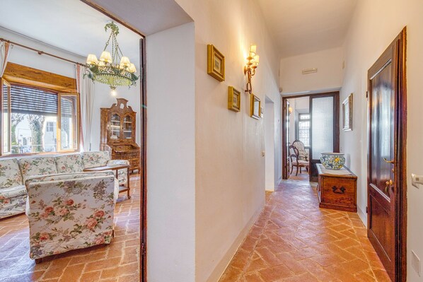 A hallway with a floral sofa, a wooden cabinet, and a chandelier. - Chianti Classico Home Panoramic View (Castellina in Chianti)