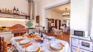 A dining area with a table set for six, kitchen appliances, and a view into the living room. - Chianti Classico Home Panoramic View (Castellina in Chianti)