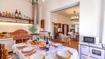 Comedor con una mesa dispuesta para seis personas, electrodomésticos y vista al salón.
