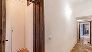 A hallway with a white door, a wooden door frame, and a light switch on the wall.