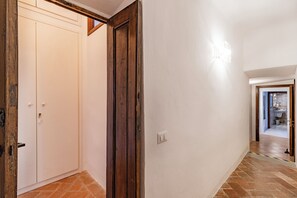 Un couloir avec une porte blanche, un chambranle en bois et un interrupteur sur le mur.
