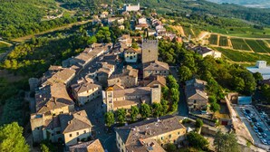 An aerial view of a historic town with a prominent tower, narrow streets, and surrounding vineyards. - Chianti Classico Home Panoramic View (Castellina in Chianti)