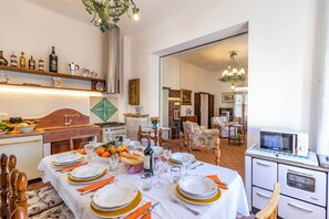 A dining area with a table set for six, a kitchen with vintage appliances, and a cozy living room with a fireplace. - Chianti Classico Home Panoramic View (Castellina in Chianti)