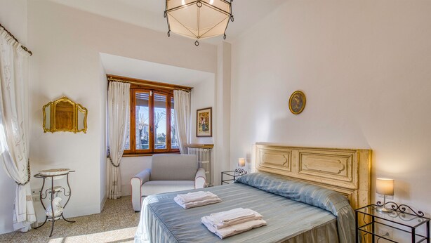 Une chambre à coucher avec un lit, une chaise, une table et une fenêtre avec des rideaux.
