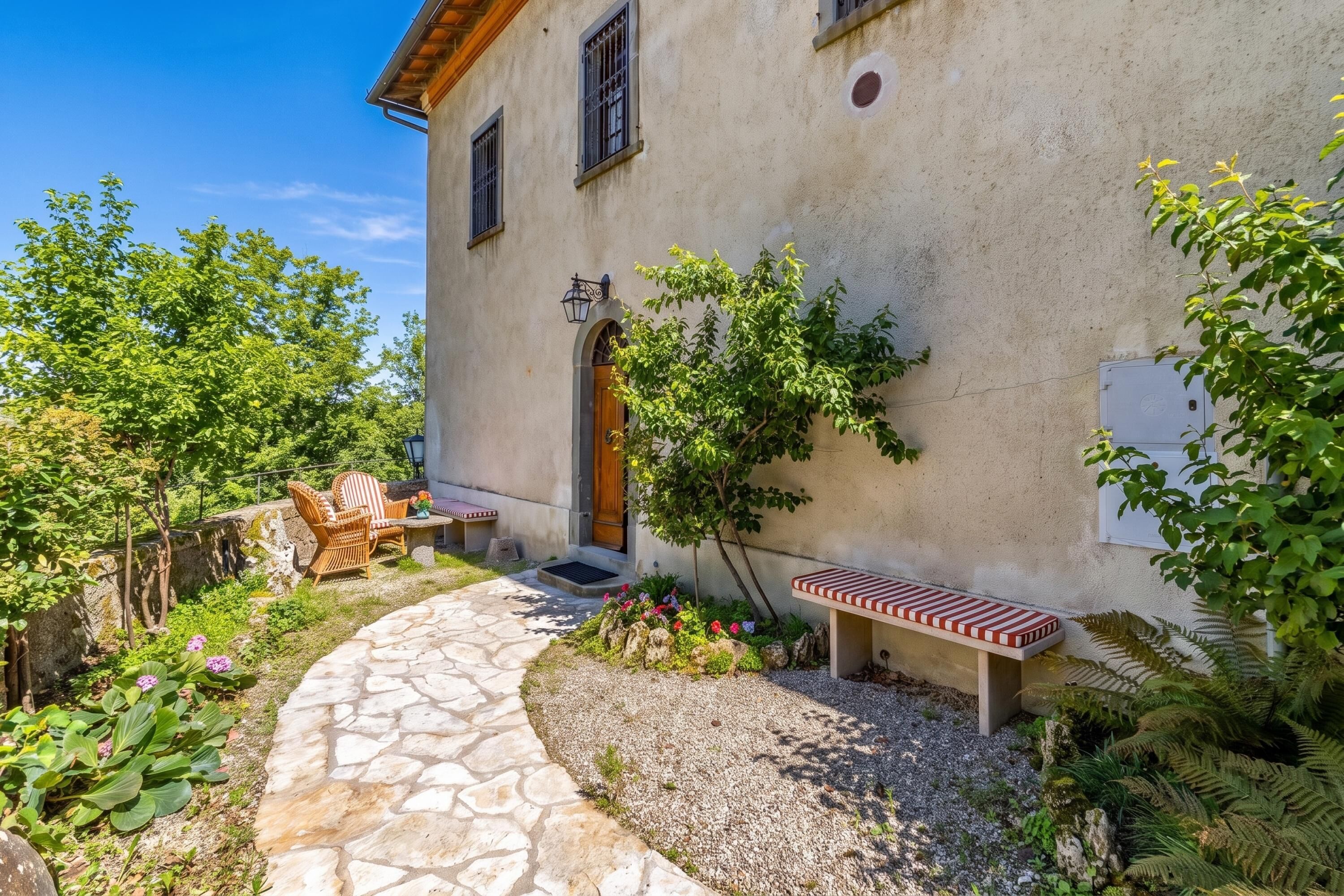 A stone pathway leading to a rustic building with a wooden door and windows.