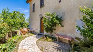 A stone pathway leading to a rustic building with a wooden door and windows.