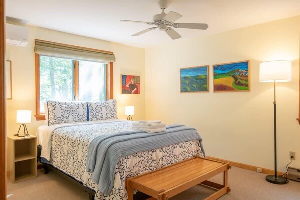 A bedroom with a bed, bedside lamps, a ceiling fan, a window with blinds, and two paintings on the wall. - 4 Mins to Wellfleet Village, Screened sunroom! (Wellfleet)