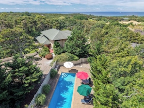 A residential property with a swimming pool, outdoor seating, and a view of the ocean.