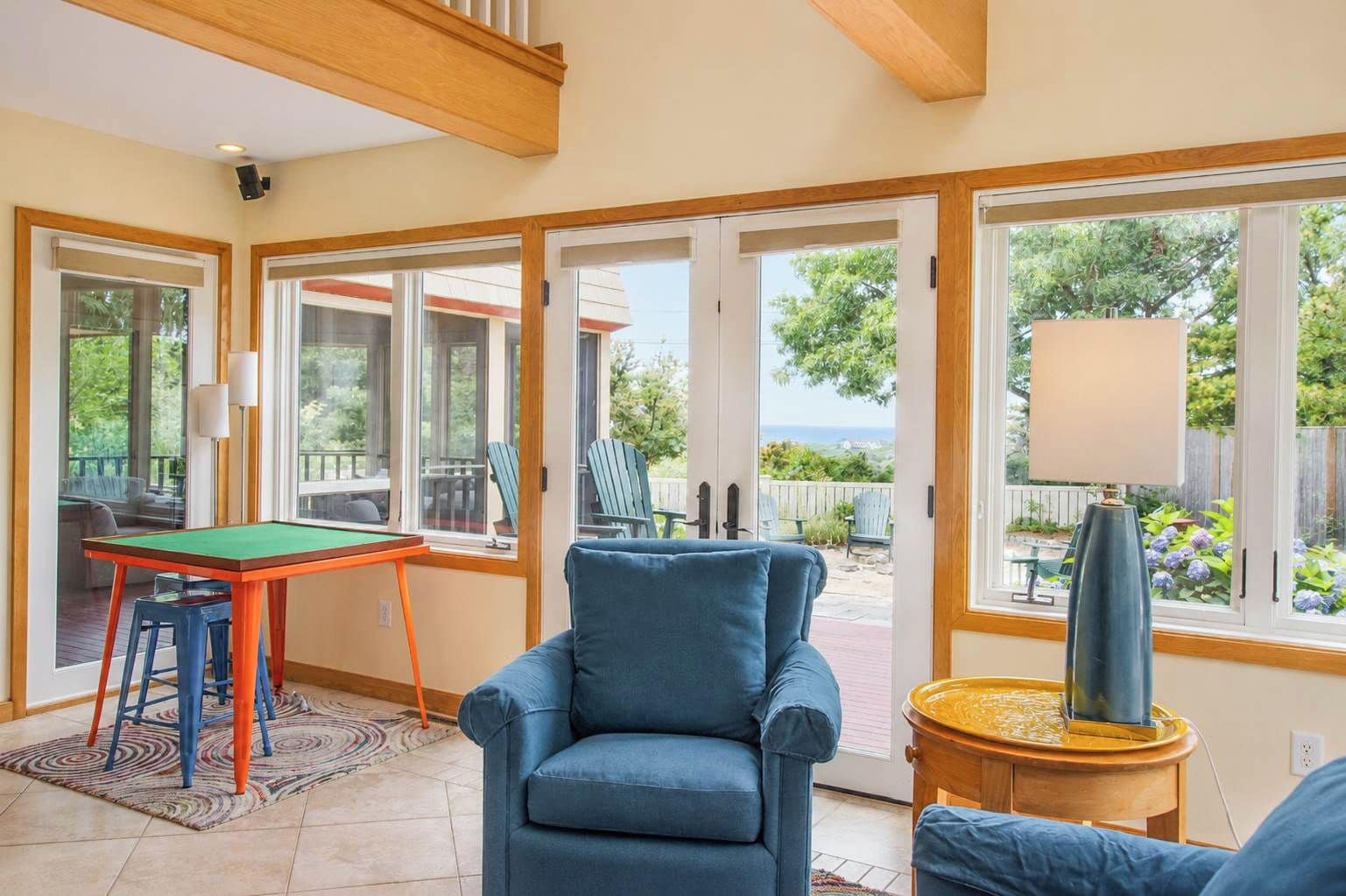 A room with a pool table, a blue armchair, and a view of the outdoors.