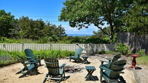 A backyard with several green Adirondack chairs, a small fire pit, and a red table. - Beautiful backyard, pool, deeded beach rights! (Truro)