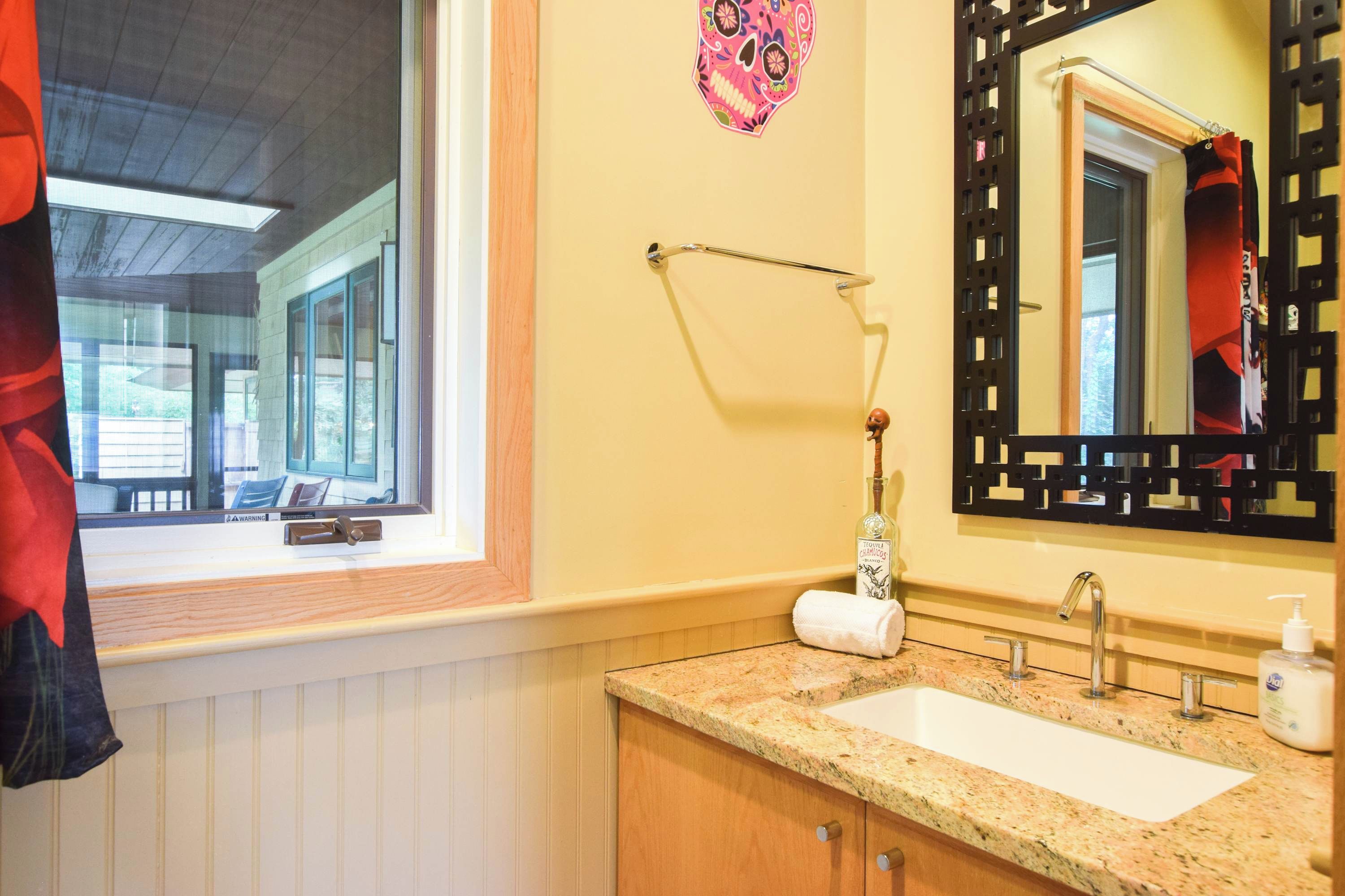 Une salle de bain équipée d’un lavabo, d’un miroir, d’une serviette et d’une fenêtre donnant sur l’extérieur.