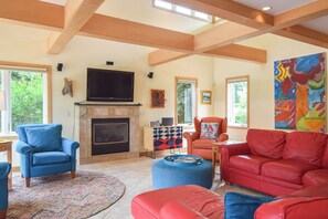 A spacious living room with a fireplace, comfortable seating, and artwork on the walls.