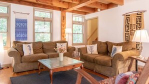 A cozy living room with two brown sofas, a glass coffee table, and a wooden ceiling. - Beautiful, private & spacious, great location, large outdoor stone patio! (Wellfleet)