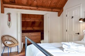 A bedroom with a bed, a chair, a wardrobe, and a door.