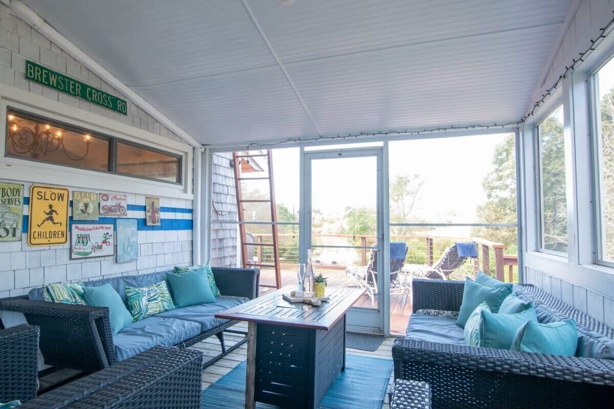 A covered patio area with wicker furniture, a table, and a view of the outdoors.