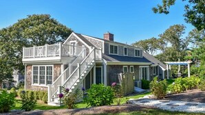 A two-story house with a balcony, a covered porch, and a well-maintained garden. - Roof Deck, Walk to Forest Beach, Fire Pit! (Chatham)
