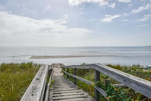 Una escalera de madera que lleva a una playa, con barandilla de madera.