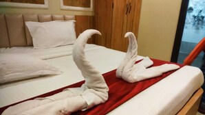 Habitación de hotel con cama, una colcha roja y dos toallas dispuestas en forma de cisne.