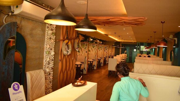 Un restaurante con cabinas, lámparas colgantes y un adorno de pared de madera.
