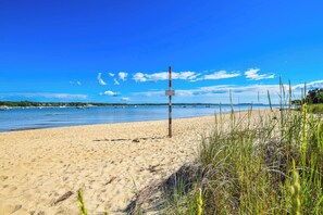 En strand med en vägskylt, en sandstrand och båtar i fjärran.