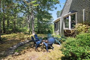 A house with a front porch, two Adirondack chairs, and a stone pathway leading to the house.