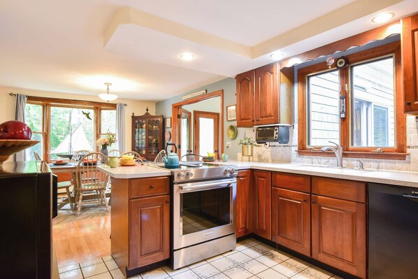 A kitchen with wooden cabinets, a stainless steel oven, a microwave, and a large window.