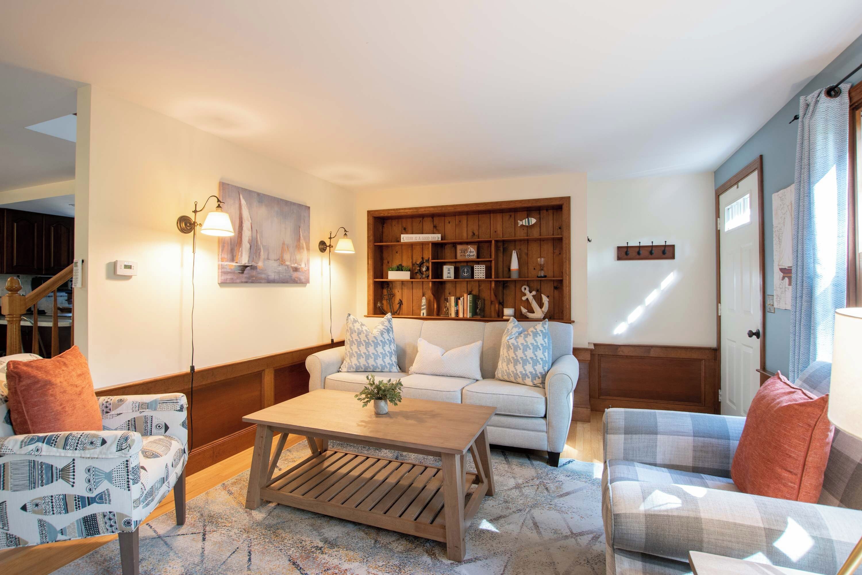Un salon comprenant un canapé, deux fauteuils, une table basse et une bibliothèque en bois.