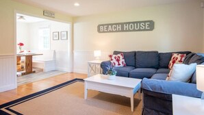 Una sala de estar con un sofá, una mesa de centro y un letrero que dice 'BEACH HOUSE'.