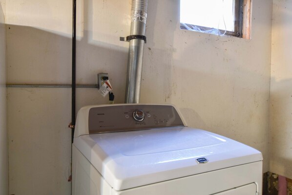 A white washing machine with a control panel, a metal exhaust pipe, and a window with a view of the sky. - Dogs welcome, huge yard right next to Rail Trail! (Harwich)