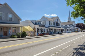 A street with buildings, including a bar named 'OYSTER BAR' and a church with a steeple. - Dogs welcome, huge yard right next to Rail Trail! (Harwich)