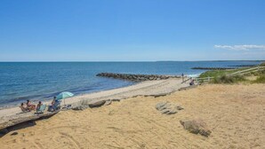 A beach with people relaxing, a wooden walkway, and a clear blue sky. - Hot Tub, 200 ft to Beach! (Dennis)