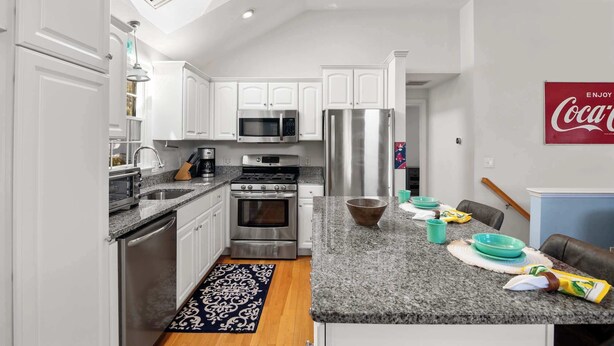 A modern kitchen with white cabinets, stainless steel appliances, and a granite countertop. - Hot Tub, 200 ft to Beach! (Dennis)