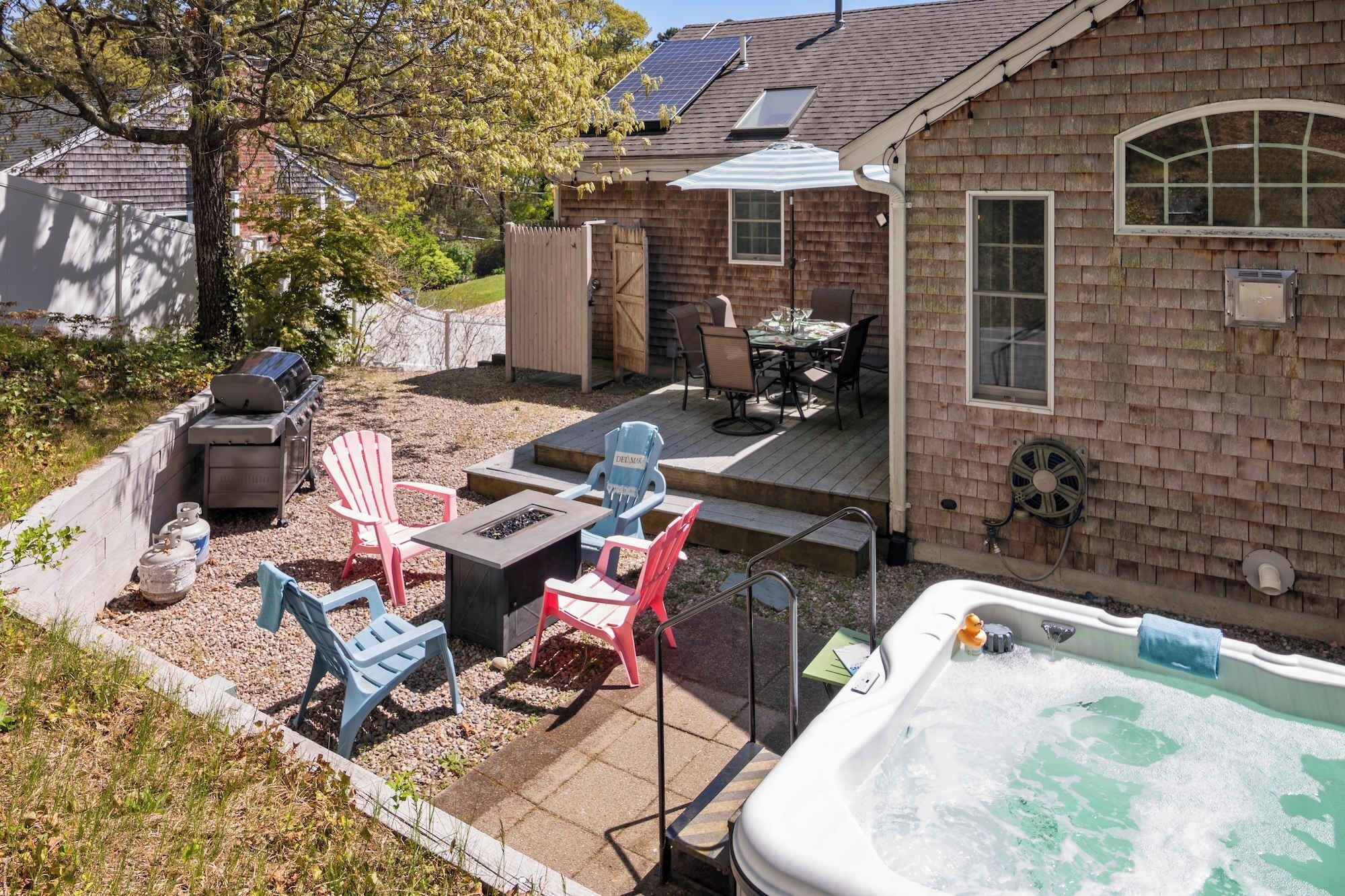 Un patio trasero con un jacuzzi, muebles de jardín y una parrilla.