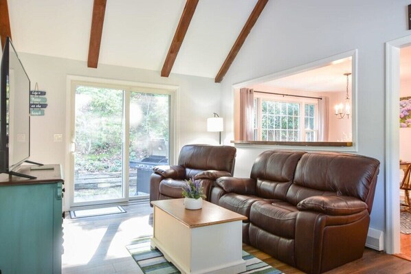 A living room with a brown leather sofa, a wooden coffee table, and a sliding glass door leading to an outdoor area.