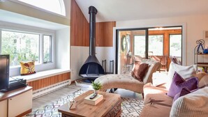 A cozy living room with a fireplace, large windows, and a comfortable seating area. - Lake House in Centerville with Private Water Access! (Barnstable)