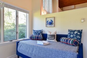 A bedroom with a bed, pillows, a framed picture, and a window.