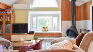 A cozy living room with a fireplace, a television, and a bookshelf. - Lake House in Centerville with Private Water Access! (Barnstable)