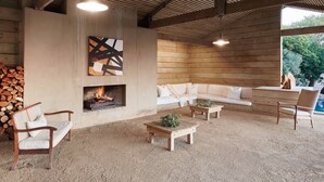 Uma sala de estar aconchegante com lareira, móveis de madeira e uma grande janela com vista para o verde.
