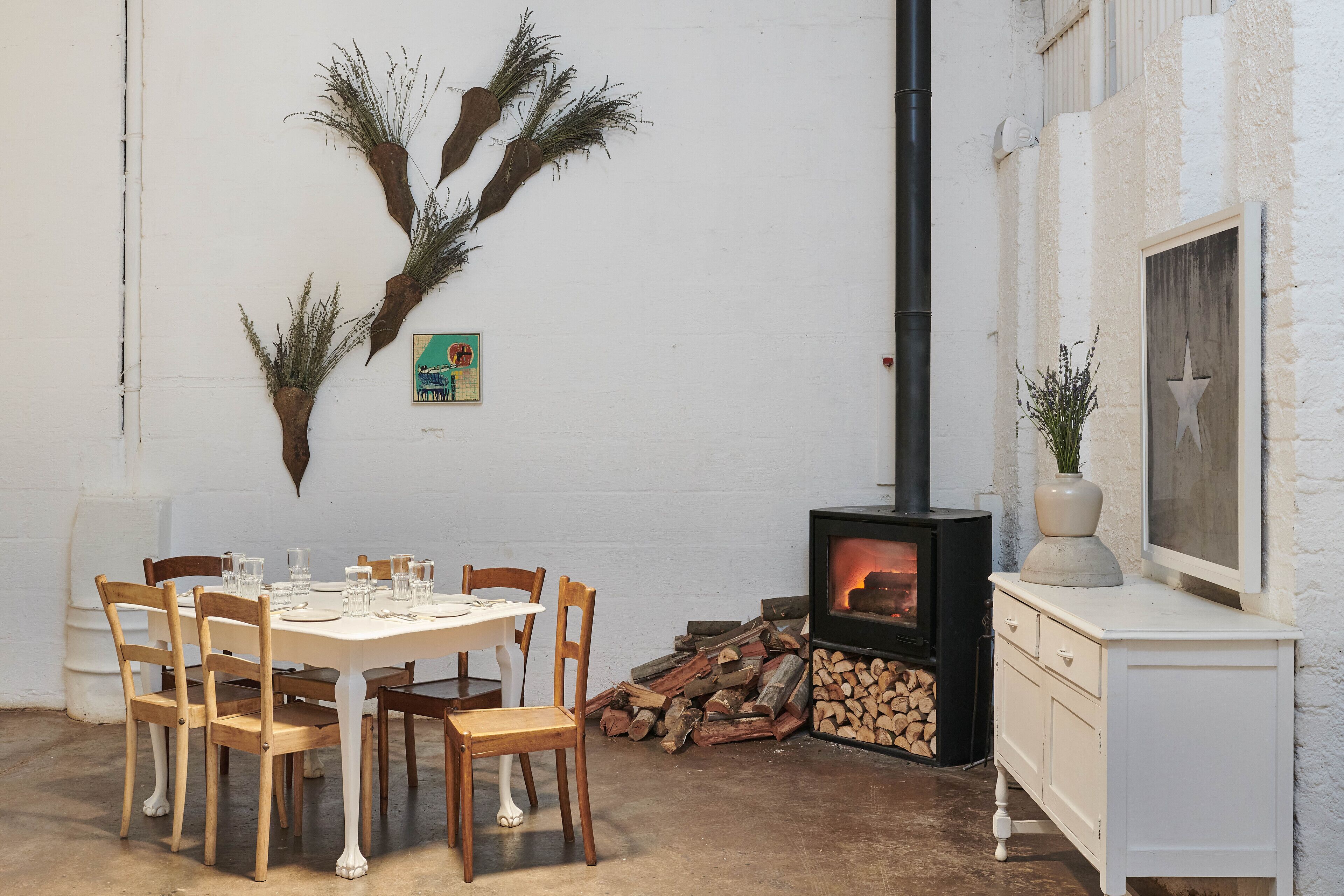 Un comedor con una mesa redonda, sillas de madera, un armario blanco y una chimenea.