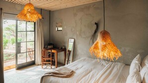 Quarto com cama, escrivaninha e luminária suspensa.