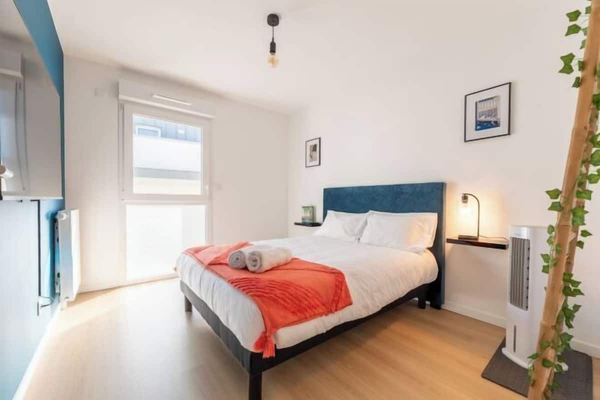 Quarto com cama, radiador, janela e um quadro na parede.