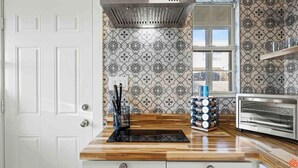 Una cocina con baldosas estampadas, encimera de madera, horno empotrado y ventana con vistas.