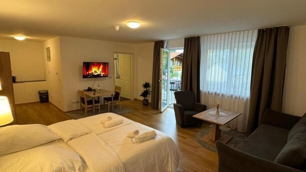A hotel room with two beds, a sofa, a small table, a TV, and a fireplace. - Motel Zur Dachsbaude (Wandlitz)