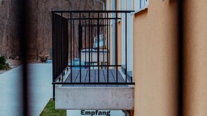 A building with a wooden balcony, a concrete base, and a sign labeled "Empfang". - Motel Zur Dachsbaude (Wandlitz)