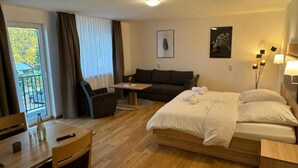 A hotel room with a bed, a sofa, a dining table, and a small table. - Motel Zur Dachsbaude (Wandlitz)